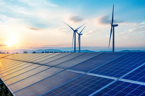 a solar farm with windmills in the background during a partly cloudy day