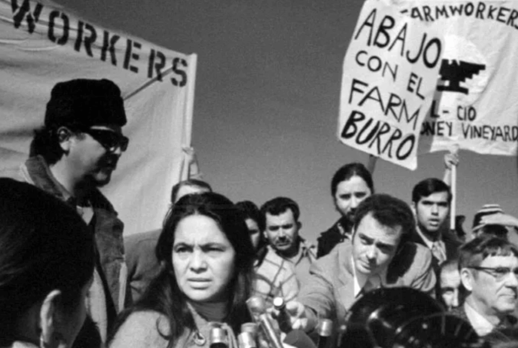 Photo of labor leader Dolores Huerta surrounded by press.